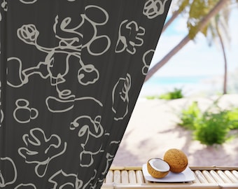 May include: A black sheer curtain with a white abstract pattern hangs in front of a tropical beach scene. Two halves of a coconut are on a white plate on a bamboo table.