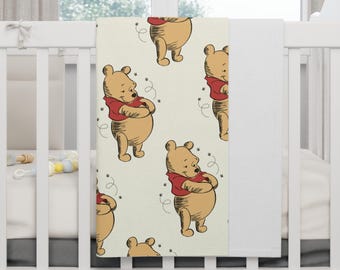 May include: A cream-colored baby blanket with a repeating pattern of Winnie the Pooh hugging himself. The blanket features a red, yellow, and brown color scheme.