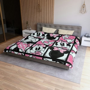 May include: A pink and black bedding set featuring a cartoon image of Minnie Mouse. The bedding is made of soft, comfortable fabric and is perfect for any Disney fan.
