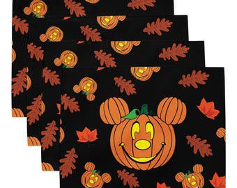 May include: A set of four rectangular placemats featuring a black background with a repeating pattern of orange pumpkin jack-o'-lanterns shaped like mouse ears and scattered brown and red autumn leaves. The design includes a large central pumpkin.