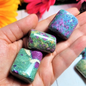 Könnte beinhalten: Drei grüne und violette Rubinzoisite-Trommelsteine. Die Steine sind glatt und poliert und haben eine Vielzahl von grünen und violetten Farbtönen.