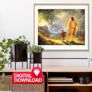 Puede incluir: Una descarga digital de una pintura que representa a Jes&uacute;s caminando con un ni&ntilde;o en un entorno boscoso. La pintura presenta una cascada, un arroyo y un exuberante bosque verde. La pintura est&aacute; enmarcada en un marco de madera claro.