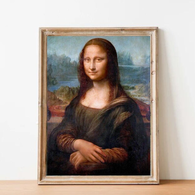 May include: A framed reproduction of the Mona Lisa painting. The painting depicts a woman with a soft smile, wearing a dark dress and a light background.