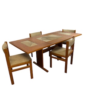 May include: A rectangular wooden dining table with three inset ceramic tiles featuring geometric patterns, accompanied by four matching wooden chairs with beige fabric upholstered seats and backrests, arranged around the central table structure.