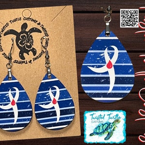 May include: A pair of blue and white teardrop-shaped earrings with a white ribbon and a red drop design. The earrings are on a brown card with the text "Twisted Turtle Customs".