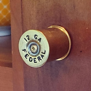 Puede incluir: Una taza de cerámica blanca con un asa negra y el texto "But First, Coffee" en negrita negra. La taza está sobre una superficie blanca. La taza mide 10 cm de alto.