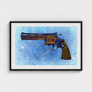 May include: A framed wall art print featuring a side profile of a revolver rendered in shades of brown and gold. The firearm is set against a textured, mottled light blue background with a watercolor effect, enclosed in a simple black frame.