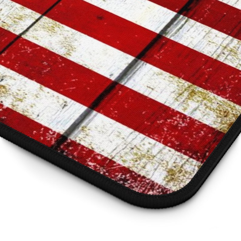 Puede incluir: Una bandera estadounidense roja, blanca y azul impresa en una superficie de madera. La bandera est&aacute; desgastada y descolorida, lo que le da un aspecto vintage.