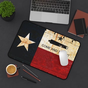 May include: A mouse pad featuring a distressed, vintage-style Texas flag with the words "Come and Take It" and a cannon. The flag is red, white, and blue with a single white star in the blue section.