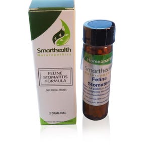 May include: A 2 dram vial of Smarthealth Naturopathics Feline Stomatitis Formula homeopathic pellets. The vial is labeled with the product name and instructions for use. The vial is sitting on a white surface.