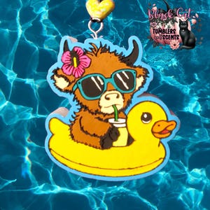 May include: A whimsical, cartoon-style charm featuring a brown cow wearing sunglasses and a flower, floating on a yellow duck floatie. The cow is holding a drink with a straw. The charm is set against a blue water background.