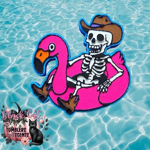 May include: A whimsical design featuring a skeleton wearing a cowboy hat and boots, riding a pink flamingo pool float. The float has a blue outline, and the skeleton is white. The background is a blue water pattern.