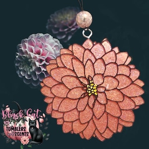 May include: A pink glitter resin flower charm with a yellow center. The charm is hanging from a string with a clear bead.
