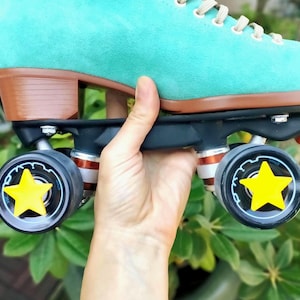 May include: Teal suede roller skate with brown wheels and black trucks. The wheels have yellow star-shaped stickers.