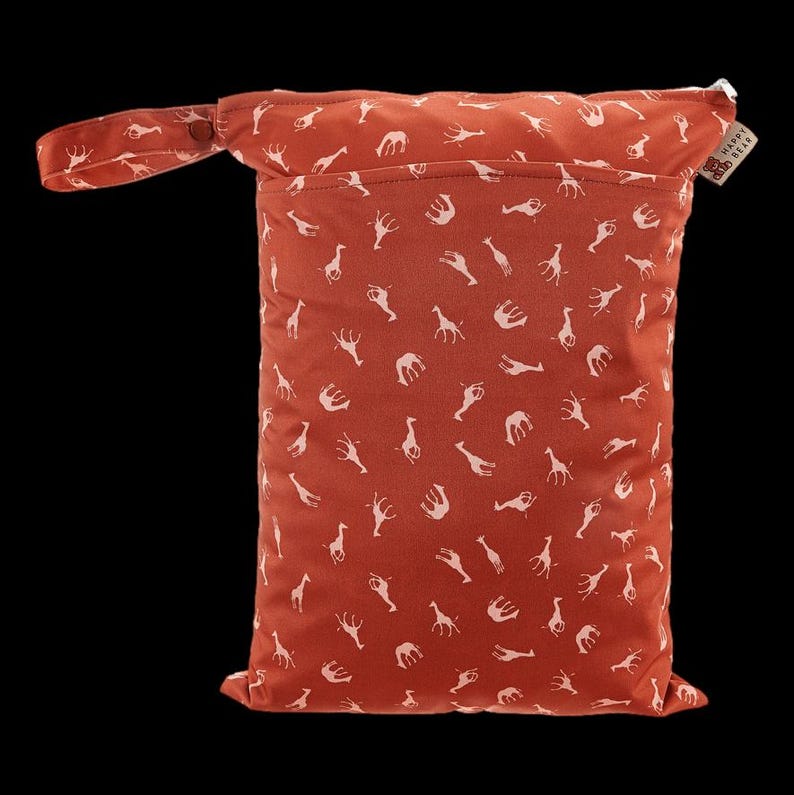 Puede incluir: Una bolsa h&uacute;meda reutilizable de color &oacute;xido con un estampado de jirafas blancas. La bolsa tiene un asa con cierre de bot&oacute;n a presi&oacute;n y un bolsillo en la parte delantera. Una peque&ntilde;a etiqueta con el texto "HAPPY BEAR" est&aacute; adjunta.