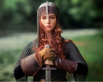 Op de afbeelding: Een vrouw in een kettingbaard met een zwaard, die een helm met een kettingbaardcoif draagt en het zwaard voor zich houdt.