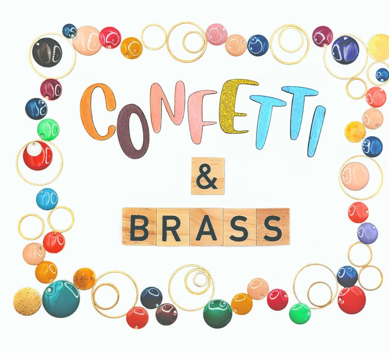 K&ouml;nnte beinhalten: Dekoratives Bild mit den Worten "Confetti & Brass" in farbenfrohen Buchstaben und Holzfliesen. Das Design umfasst einen Rand aus bunten Perlen und goldfarbenen Drahtkreisen, wodurch eine festliche und k&uuml;nstlerische Komposition entsteht.