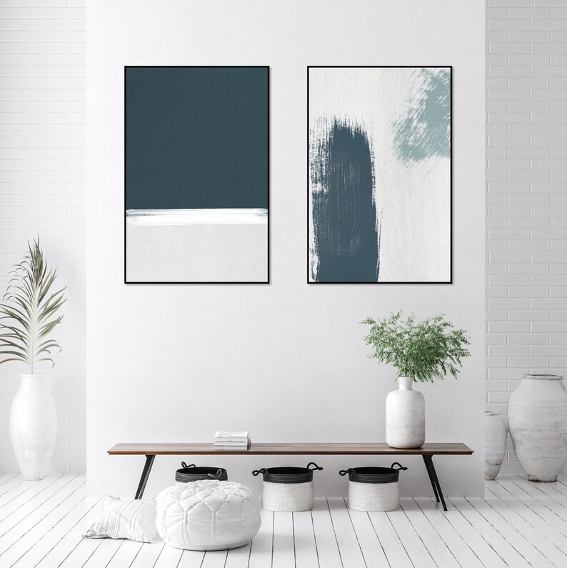 May include: Two abstract art prints with a white background and blue brushstrokes. The print on the left has a solid blue rectangle at the top and a white horizontal line at the bottom. The print on the right has a large blue brushstroke in the center.