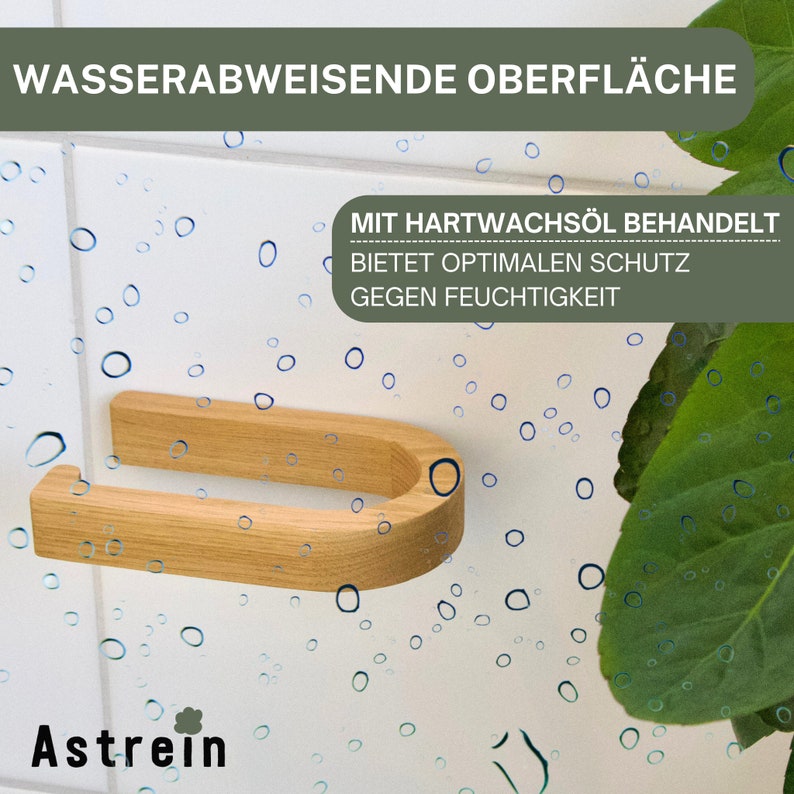 May include: A wooden toilet paper holder with a U-shaped design. The holder is made of natural wood and has a water-resistant finish. The text "MIT HARTWACHS&Ouml;L BEHANDELT BIETET OPTIMALEN SCHUTZ GEGEN FEUCHTIGKEIT" is visible on the holder.