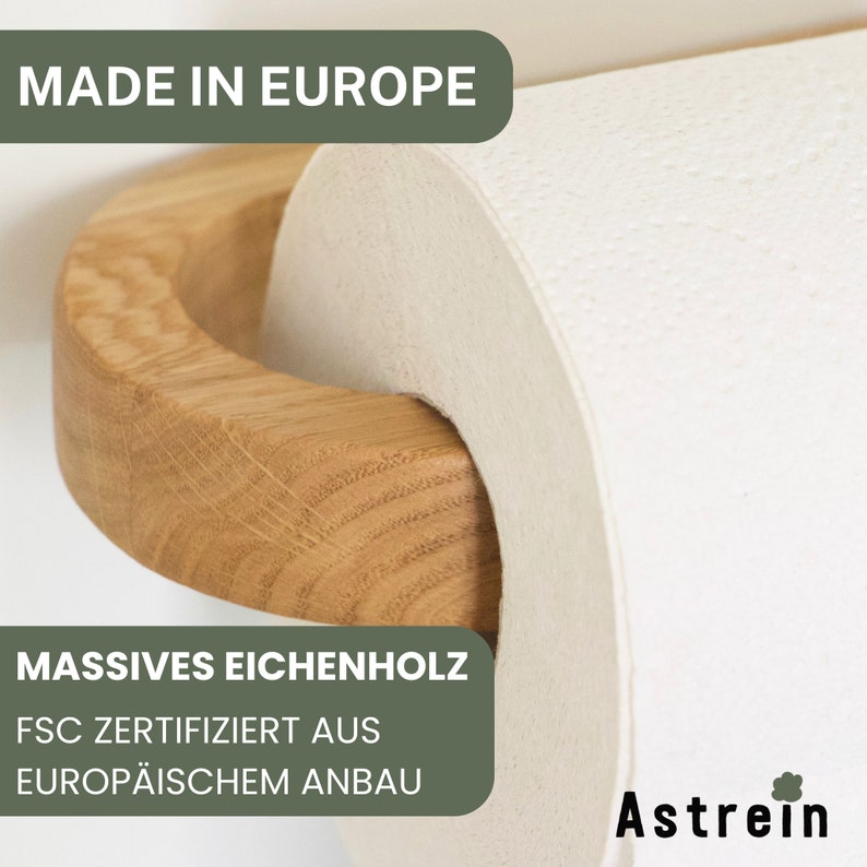 May include: A wooden paper towel holder with a white paper towel roll. The holder is made of solid oak wood and is certified by the Forest Stewardship Council (FSC) from European forests. The text "MADE IN EUROPE" and "MASSIVES EICHENHOLZ FSC ZERTIFIZIERT AUS EUROP&Auml;ISCHEM ANBAU" is visible on the image. The brand name "Astrein" is also visible on the image.