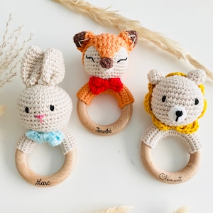 May include: Three wooden baby teethers with crocheted animal heads. The teethers are personalized with the names "Marc", "Timoth&eacute;e", and "Clement". The animals are a fox, a bunny, and a lion.