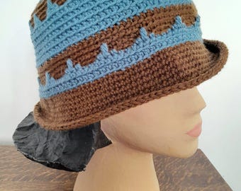 May include: A brown and blue crocheted hat with a wide brim. The hat has a geometric pattern with alternating stripes of brown and blue.