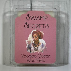 May include: A clear plastic clamshell package containing wax melts. The label is pink with the words "Swamp Secrets" and "Voodoo Queen Wax Melts." An illustration of a woman wearing a head wrap and jewelry is also on the label.