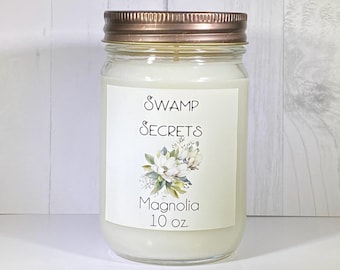 May include: A 10 ounce candle in a clear glass jar with a copper lid. The label reads "Swamp Secrets" and "Magnolia".