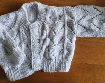 Hand knitted baby cardigan in soft pale grey wool. Elaborate pattern with matching buttons.