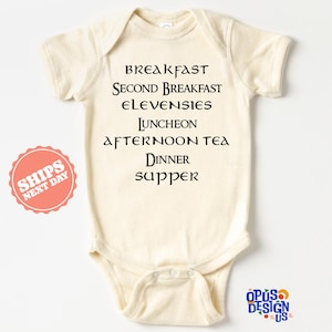May include: A white baby onesie with black text that reads "Breakfast, Second Breakfast, Elevensies, Luncheon, Afternoon Tea, Dinner, Supper".