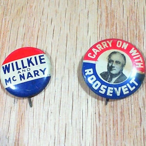 May include: Two vintage political campaign buttons. One button has the text "WILLKIE AND McNARY" in white on a red and blue background. The other button features a portrait and the text "CARRY ON WITH ROOSEVELT".