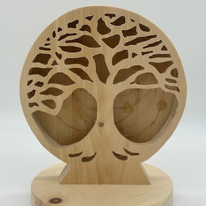 Può includere: Una scultura in legno di albero della vita con una base circolare e tagli intricati. La scultura è illuminata da luci LED bianco caldo.