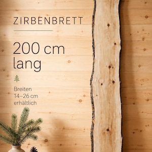 Może przedstawiać: Długa, jasna deska drewniana z naturalnymi krawędziami i widocznymi sękami. Tekst na obrazie brzmi ZIRBENBRETT, 200 cm lang, oraz Breiten 14-26 cm erhältlich. Obok znajduje się mały wazon z gałązkami sosny i szyszkami.