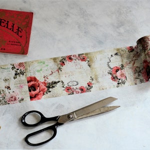 May include: Decorative washi tape roll featuring a vintage floral design with red and pink roses, script, and ornate frames. A red book with gold lettering and scissors are also in the image. Ideal for scrapbooking and crafts.