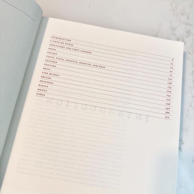 May include: Open cookbook page with a detailed table of contents. The headings include "Introduction", "Appetizers", "Soups", "Salads", "Pasta", "Seafood", "Poultry", "Meat", "Side Dishes", "Breads", "Desserts", "Basics", "Menus", and "Index".