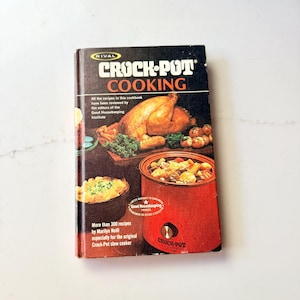 May include: Vintage "Crock-Pot Cooking" cookbook. The cover features a roasted chicken, vegetables, and a red slow cooker. The book has the "Good Housekeeping" seal of approval and includes over 300 recipes by Marilyn Neill.
