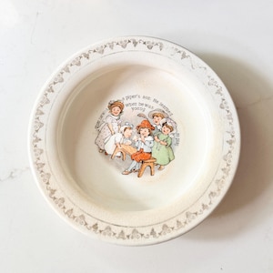Puede incluir: Cuenco de cerámica color crema con un borde decorativo y una ilustración central. La ilustración representa un grupo de niños y adultos con el texto "a piper's son. He learned to play when he was young."