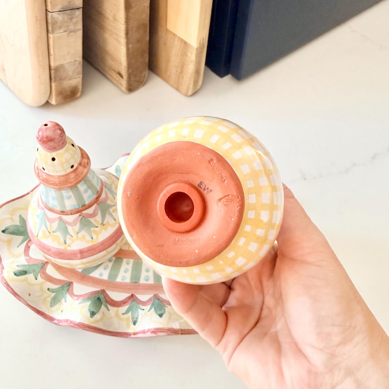 Pu&ograve; includere: Un set di saliera e pepiera in ceramica con motivo a quadretti gialli e bianchi. Un pezzo ha una forma a campana con base in terracotta e tappo, mentre l'altro &egrave; conico con una parte superiore rosa e dettagli verdi.