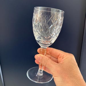 Könnte beinhalten: Ein klares Weinglas aus geschnittenem Kristall. Das Glas hat einen langen Stiel und einen runden Boden.