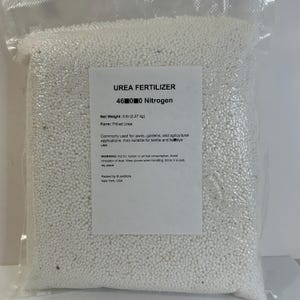 May include: A clear plastic bag filled with white prilled urea fertilizer. The label reads "UREA FERTILIZER 46-0-0 Nitrogen" and lists the net weight as 5 lb (2.27 kg). It is commonly used for lawns, gardens, and agricultural applications.