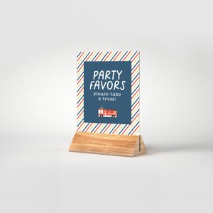 May include: A blue and white striped sign with the text "PARTY FAVORS please take a treat!" and a red fire truck illustration. The sign is on a wooden stand.