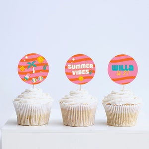 May include: Three cupcakes with pink and orange striped cupcake toppers. The toppers have different designs, one with a palm tree and sunglasses, one with the text "Summer Vibes", and one with the text "Willa is 21".