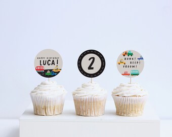 Puede incluir: Tres cupcakes decorados con adornos de papel redondos. Los adornos presentan un mensaje de cumpleaños, el número "2" y un diseño de coches coloridos con el texto "Honk! Beep! Vroom!"