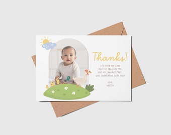 Könnte beinhalten: Eine weiße Dankeskarte mit einem Foto eines Babys in einem weißen Strampler, das auf einem grünen Grasberg mit gelben Küken und einer Ente sitzt. Der Text auf der Karte lautet "Danke! Ich habe den Kuchen und die Geschenke genossen, aber mein Lieblingsteil war das Feiern mit dir! Liebe, Harper."