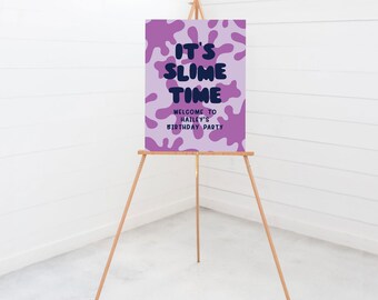 May include: Purple and white sign with the text "It's Slime Time" and "Welcome to Hailey's Birthday Party". The sign is on a wooden easel.