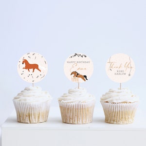 May include: Three cupcakes with white frosting and brown horse-themed cupcake toppers. The toppers say "Happy Birthday Emma", "Thank You XOXO Harlow", and a brown horse running.