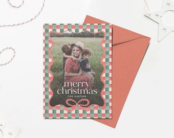 May include: A Christmas card with a red and green checkered pattern. The card features a photo of a family with a mother and two children. The text on the card reads "merry christmas" and "THE CARTERS".