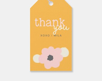 May include: A yellow thank you gift tag with a pink flower and white accents. The text on the tag reads "thank you xoxo | Mila".