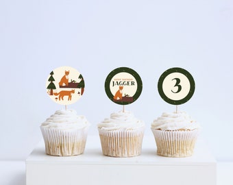 May include: Three cupcakes with green and brown themed toppers. The toppers feature a fox design, the name "Jagger" and the number "3".