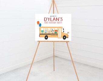 May include: A yellow school bus with animal passengers on a white background. The bus has the words "School Bus" on the side. The sign says "Welcome to Dylan's First Birthday Party!"